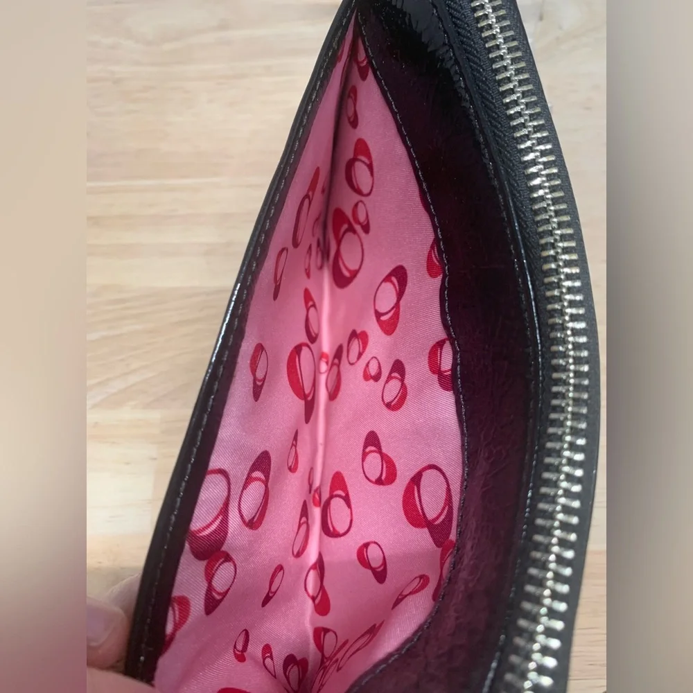 Coach Poppy Black patent leather wristlet with pink poppy interior.